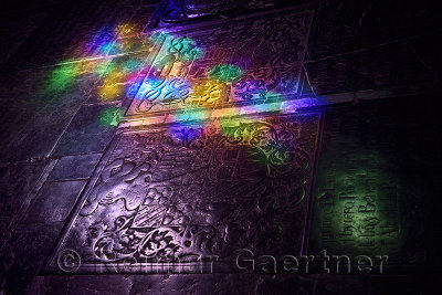 Stained glass colored light on carved tomb stone coat of arms on floor of Cordoba Cathedral Mosque