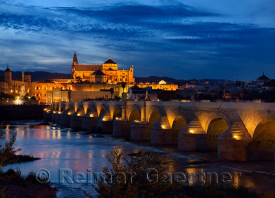 Roman Bridge over the Guadalquivir River with Episcopal Palace and Cordoba Cathedral at dusk