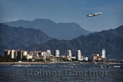 Jet plane taking off from Puerto Vallarta airport with Pacific ocean and Sierra Madre mountains