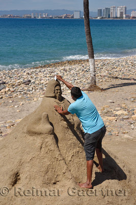 Mexican man carving a sand sculpture on the beach at Malecon Puerto Vallarta