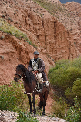 Shepherd on horseback at red rock formations Sarytau mountains Assy Plateau Kazakhstan