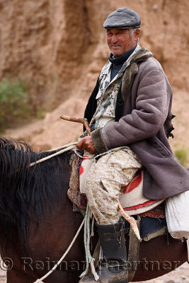 Smiling Kazakh on horseback at red rock formations Sarytau mountains Assy Plateau Kazakhstan