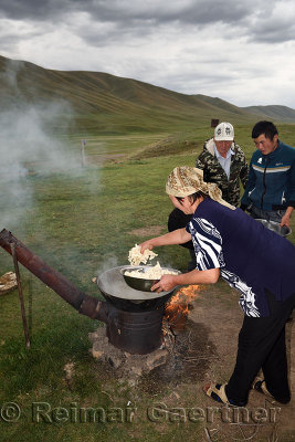Woman putting noodles in boiling lamb stew on Assy Plateau Kazakhstan