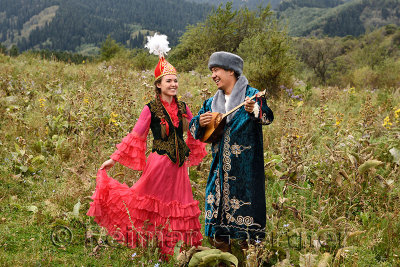 Laughing couple in traditional Kazakh cothing in a field at Huns village Kazakhstan