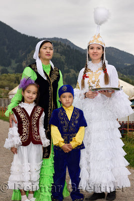 Women and children in traditional Kazakh clothes greeting quests with Shashu candies at Huns village