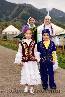 Women and walking children in traditional Kazakh clothes greeting quests with Shashu candies at Huns village