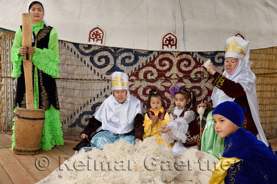 Women and children in traditional Kazakh clothes working wool into felt and yarn Huns Village Kazakhstan