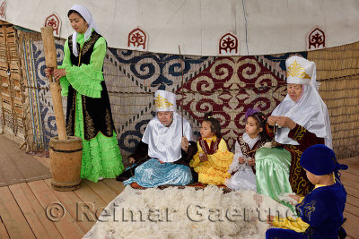 Family in traditional Kazakh clothes working wool into felt and yarn next ot a yurt at Huns Village