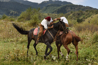 Kazakh men arm wrestling on horseback called Atpen Audaraspak in Huns Village