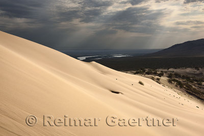 Golden sand at Singing Sand Dune Altyn Emel Park with Ili River and Kishi Kalkan mountain Kazakhstan