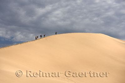 Group of photographers climbing Singing Sand Dune Altyn Emel National Park Kazakhstan