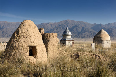 Mud brick mausoleum in cemetery at Altyn Emel Park with Koyandy Ak Tau mountain range Kazakstan