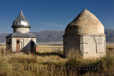 Mausoleums in cemetery on steppe of Atyn Emel Park with Koyandy Ak Tau mountain range Kazakhstan