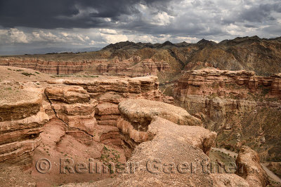 Tourists on cliff top at Charyn Canyon Park with clouds and Tien Shen mountains Kazakhstan