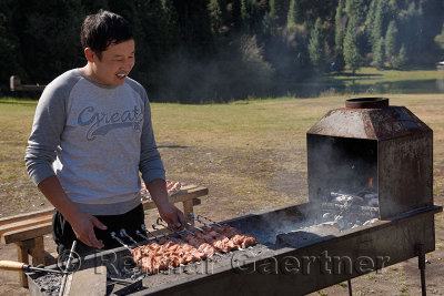 Kazakh barbecuing meat on skewers at Kaindy Lake campground Kazakhstan