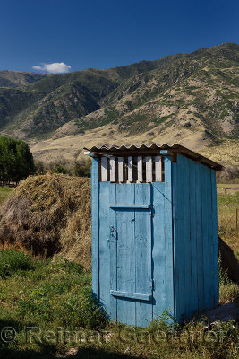 Blue outhouse with light in yard of Saty village with Kungey Alatau mountains Kazakhstan