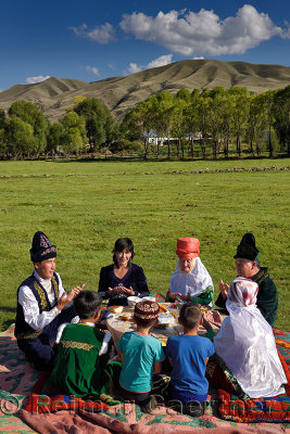 Kazakh family in traditional clothes praying before eating at a picnic in Saty Kazakhstan