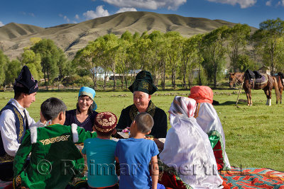 Laughing family in traditional garb at a picnic in pasture of Chilik river valley at Saty Kazakhstan
