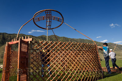 Three men setting up a yurt frame in pasture of Chilik river valley Saty Kazakhstan