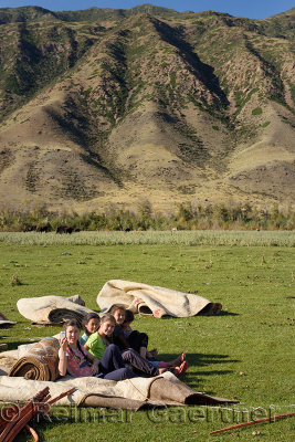 Young girls sitting on felt blankets for a yurt taking a selfie in Saty Kazakhstan