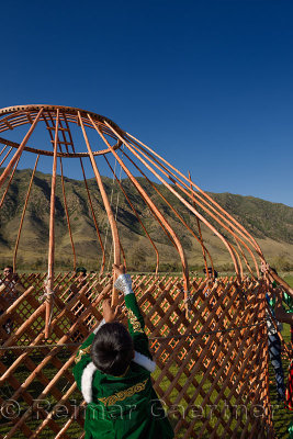 Young boy helping to assemble the wood frame of a Yurt in Saty Kazakhstan
