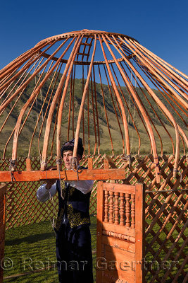 Man in traditional clothes tying the wood frame of a Yurt in Saty Kazakhstan