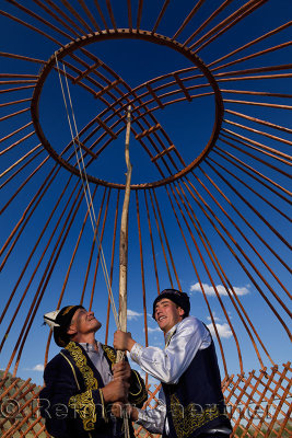 Kazakh men supporting wood frame roof of Yurt during assembly in Saty Kazakhstan