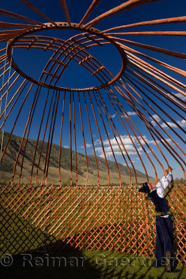 Man in traditional clothes assembling the wood frame roof of a Yurt in Saty Kazakhstan