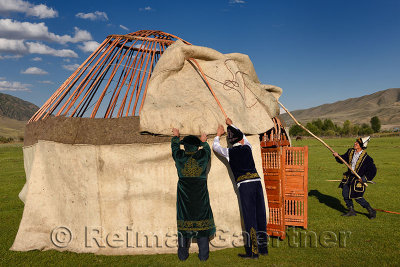 Men in traditional dress assembling wool felt covers over Yurt frame in Saty Kazakhstan