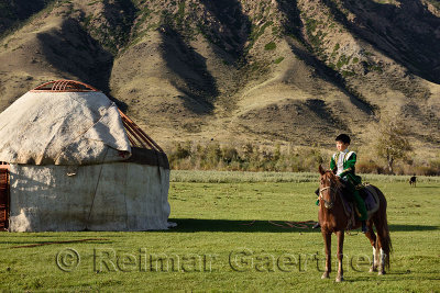 Young boy on horseback next to a partially completed Yurt at Saty Kazakhstan