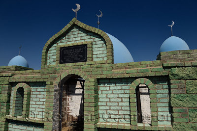 Hilal crescent moon and blue domes on Muslim green brick mausoleums at a cemetery near Shelek Kazakhstan