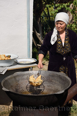 Kazakh woman draining oil from deep fried dough outdoors in Shymkent Kazakhstan