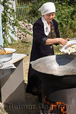 Smiling Kazakh woman placing dough into Qazan pot with oil to make Baursaki in Shymkent Kazakhstan
