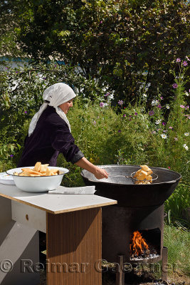 Woman in hijab cooking Baursaki fried dough in Qazan next to a home garden Shymkent Kazakhstan