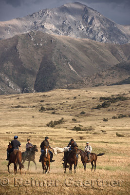 Two horse riders struggling for goat carcass in game of Kokpar Tudabarai with Talass Alatau mountain Kazakhstan