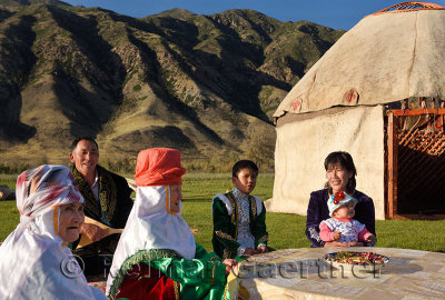 Family singing outdoors with Yurt under construction and Kungey Alatau mountain on the Chilik river Saty Kazakhstan