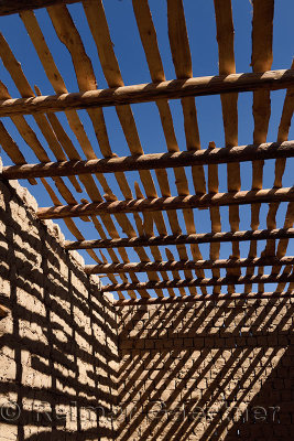 Shadows of timber beams and wood ceiling slats on mud brick walls of house under construction near Shymkent Kazakhstan