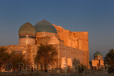 Gold glow on Khoja Ahmed Yasawi and Rabiga Sultan Begim mausoleums at sunset in Turkistan Kazakhstan