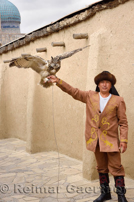 Great Horned Owl and handler with ribbed dome of Khoja Ahmed Yasawi mausoleum Turkestan Kazakhstan
