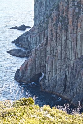 Dolerite sea columns.  At the base, a sea cave.