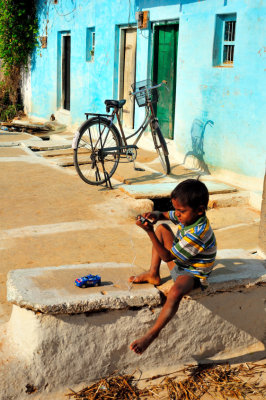 Typical, Traditional Vilagge. Boy Playing With Chinese Electric Toy