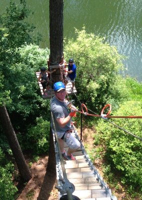Adam climbing one of the ladders to the highest zip line over the lake
