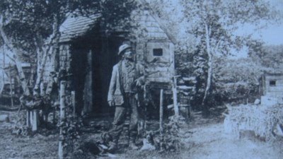 Erastus in Front of His Hunting Lodge with two Dogs