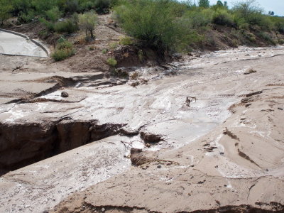 Half the road collapsed into this arroyo (see dirt tire tracks from left to right, pavement is a driveway)