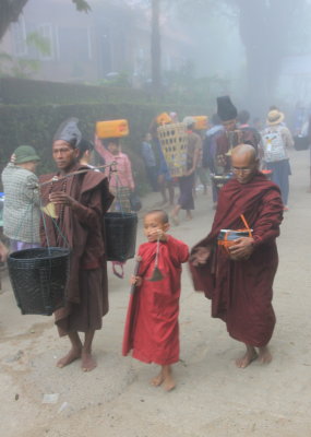Monks collecting alms in the early morning fog. My hotel in the background