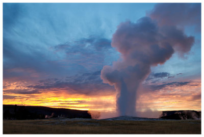 Old Faithful eruption at sunset