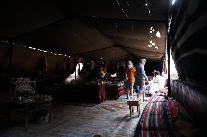 inside a bedouin merchants tent, an Italian tour group bargains...
