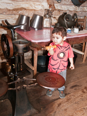 Young member of family turning crank on farm cream seperater