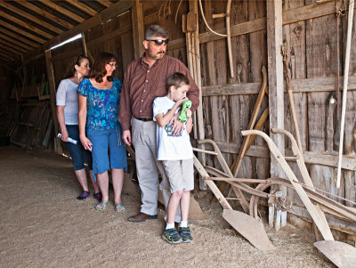 Family looking at ploughs in barn