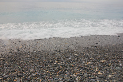 Rocks on the beach with a wave washing in.